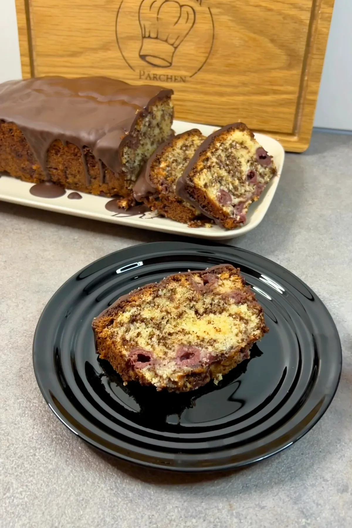 Ameisenkuchen Scheibe auf schwarzem Teller – saftig mit Kirschen und Schokolade