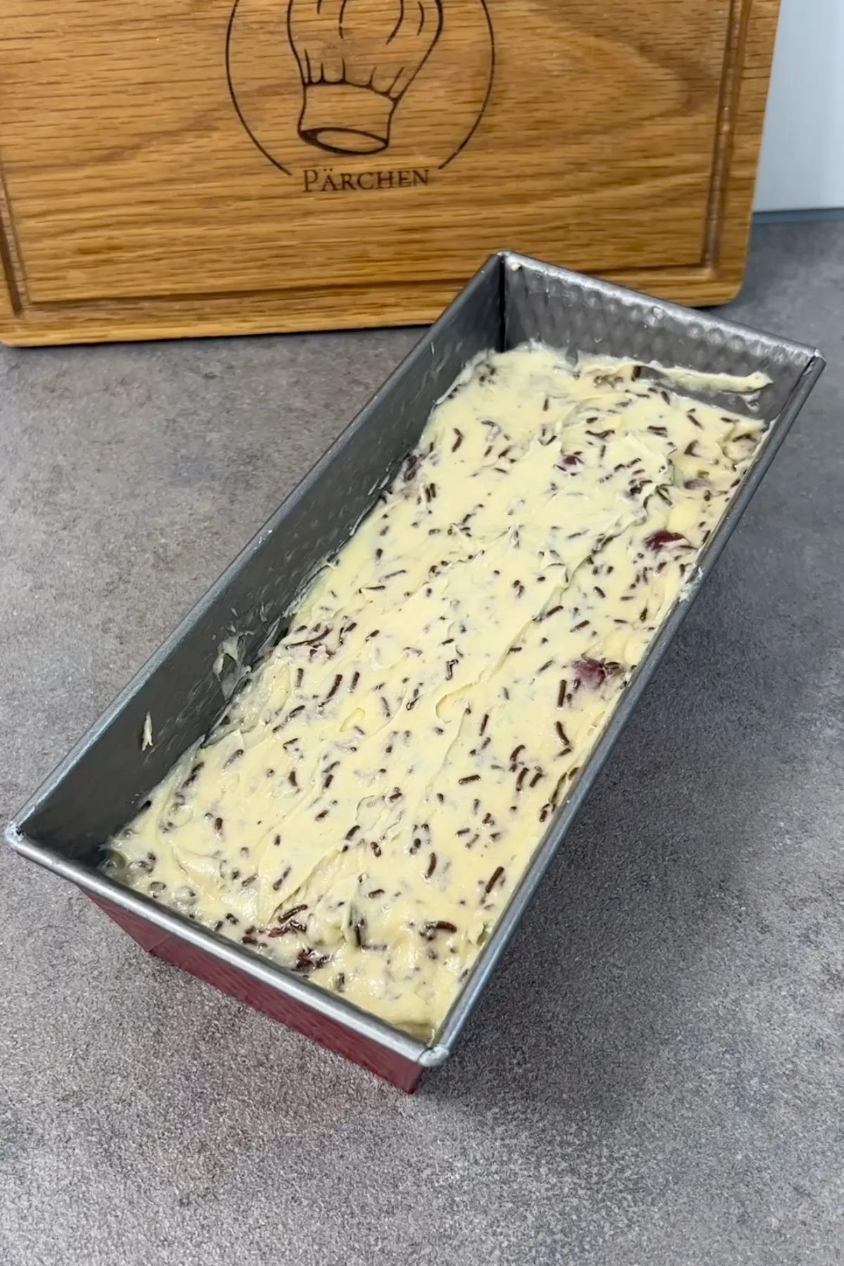 Ameisenkuchen-Teig mit Kirschen und Streuseln in der Kastenform vor dem Backen
