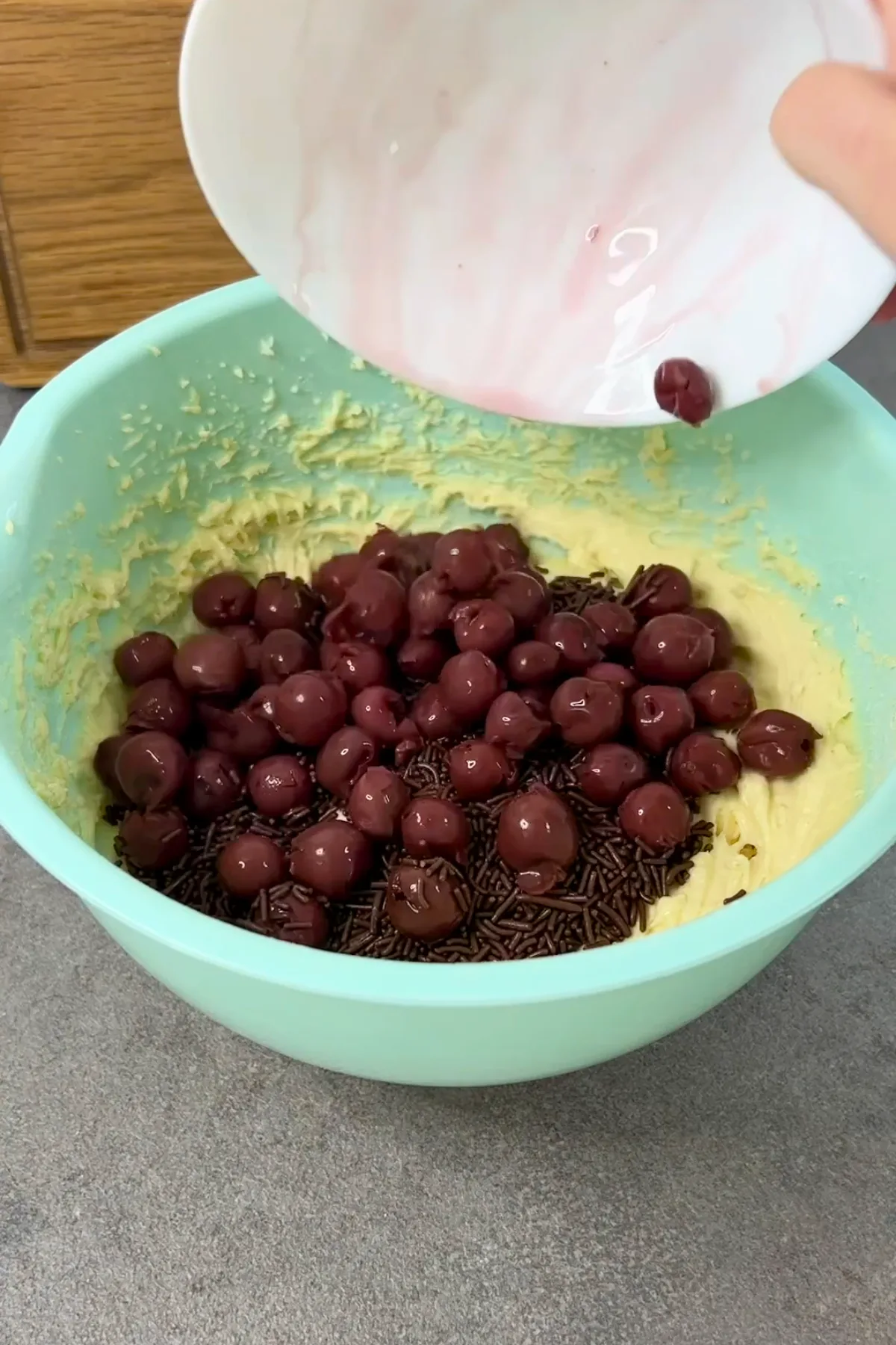 Kirschen und Schokostreusel werden in den Ameisenkuchen-Teig gegeben