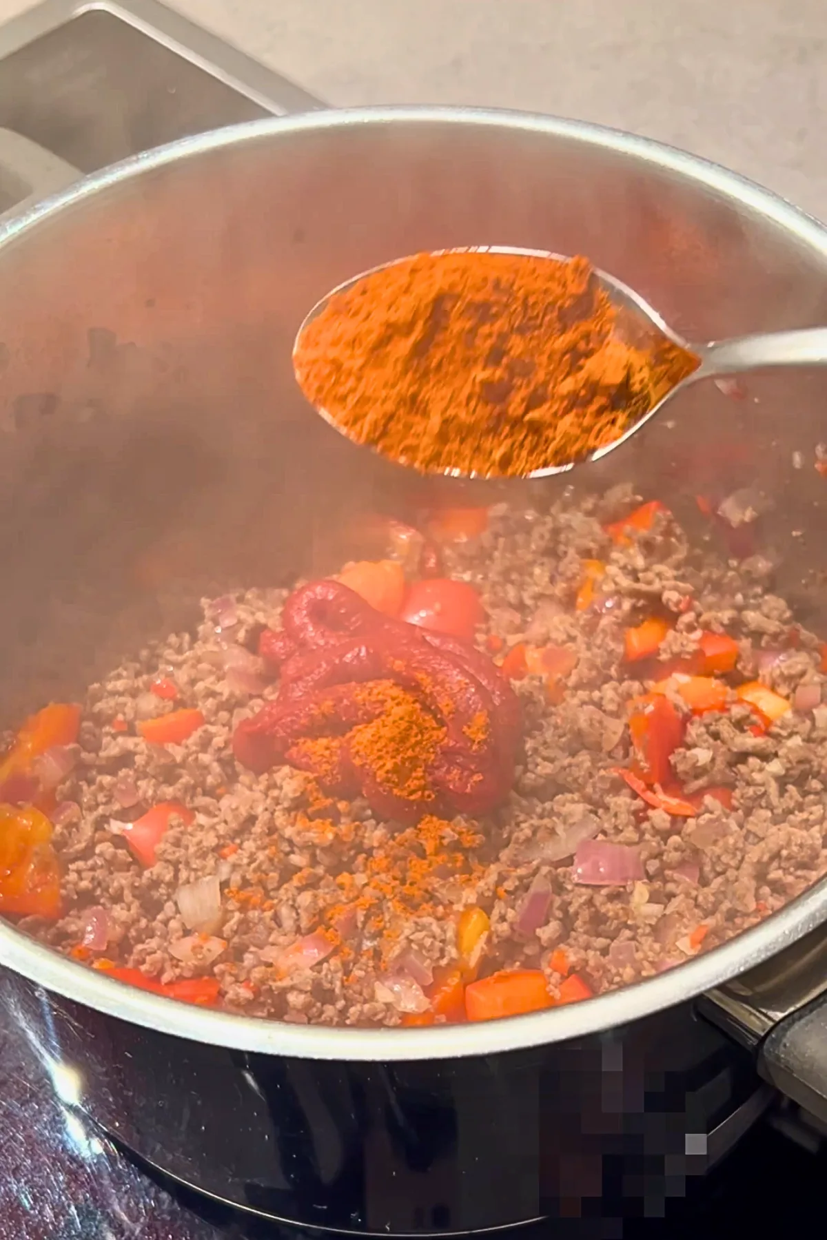 Paprikapulver wird ins Chili con Carne gegeben