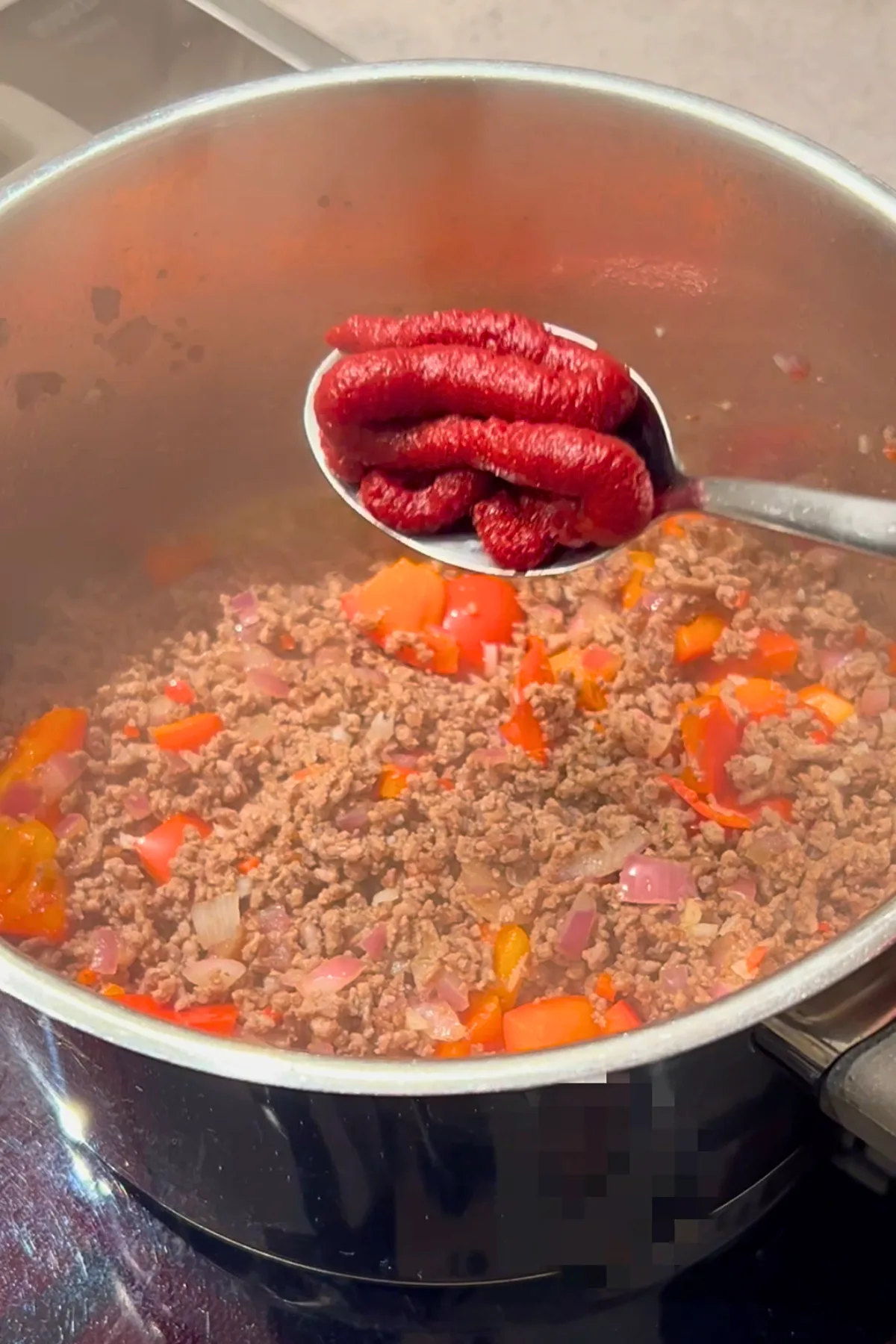 Tomatenmark wird zum Hackfleisch in den Topf gegeben