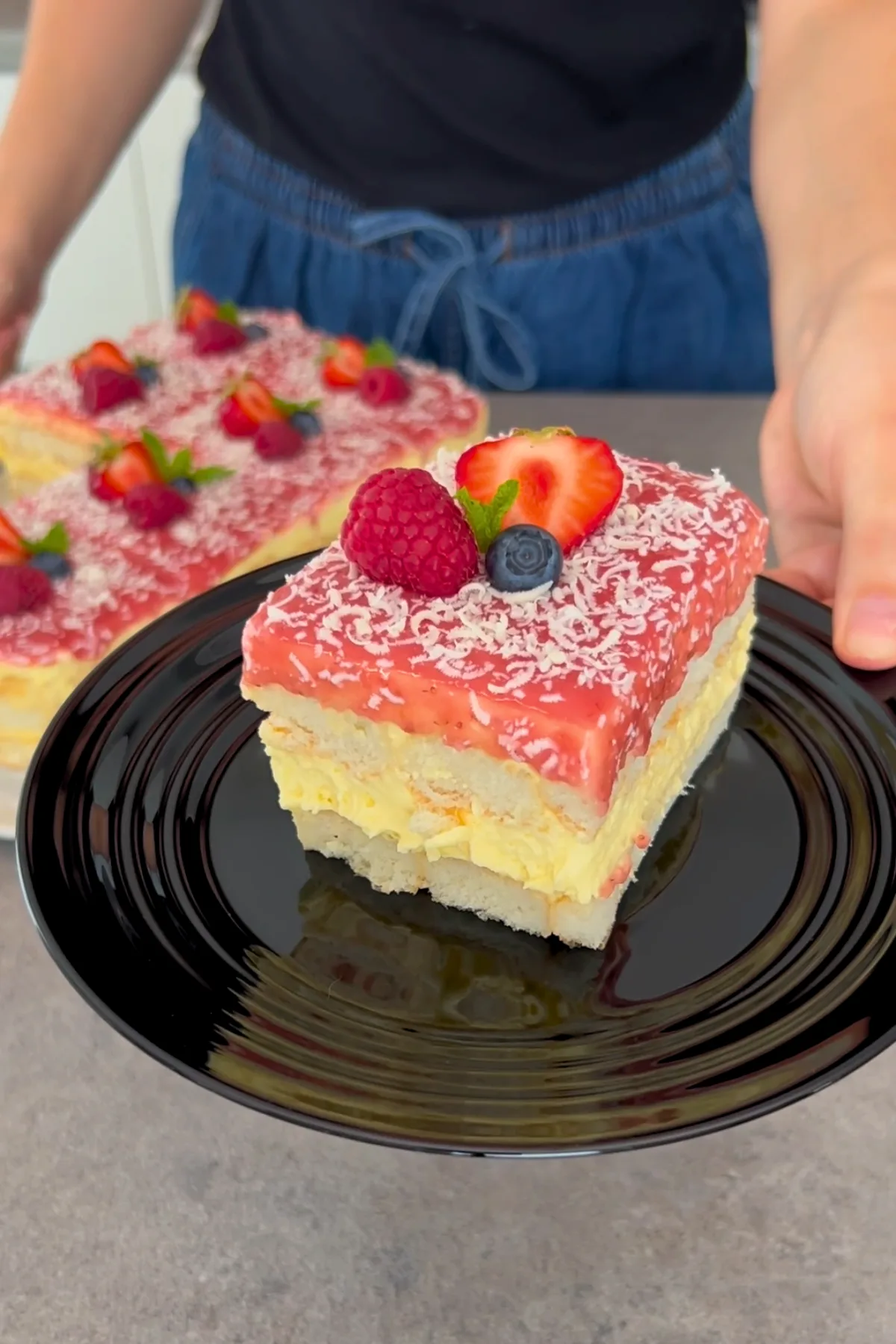 Hand hält Stück Spaghetti Eis Kuchen auf schwarzem Teller
