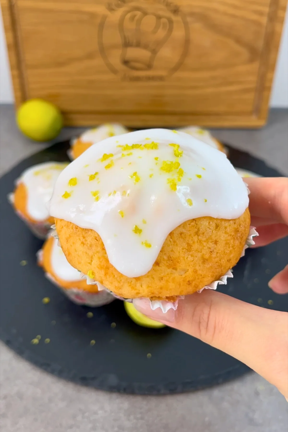 Hand hält einen saftigen Zitronenmuffin mit Zuckerglasur