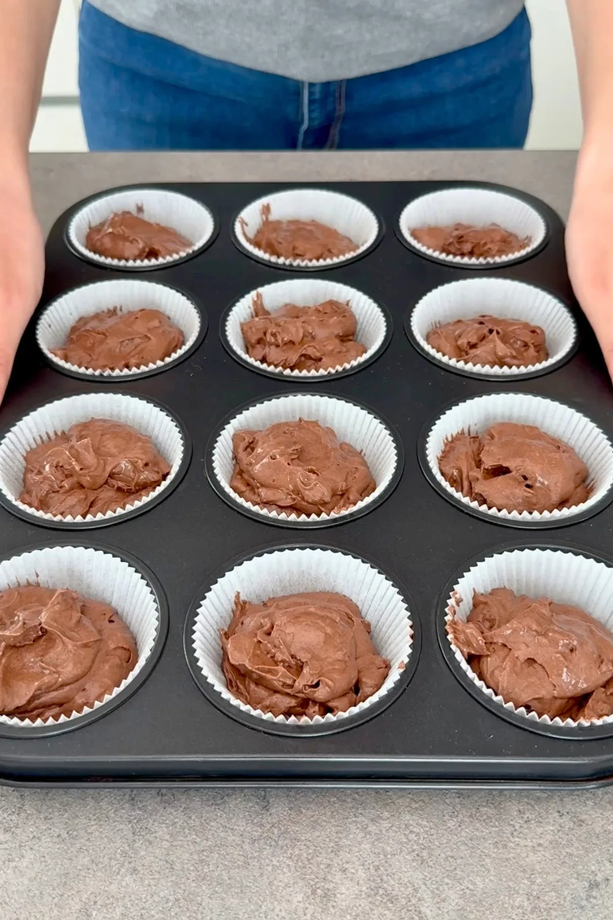 Schokoladenteig in Muffinförmchen gefüllt, bereit zum Backen