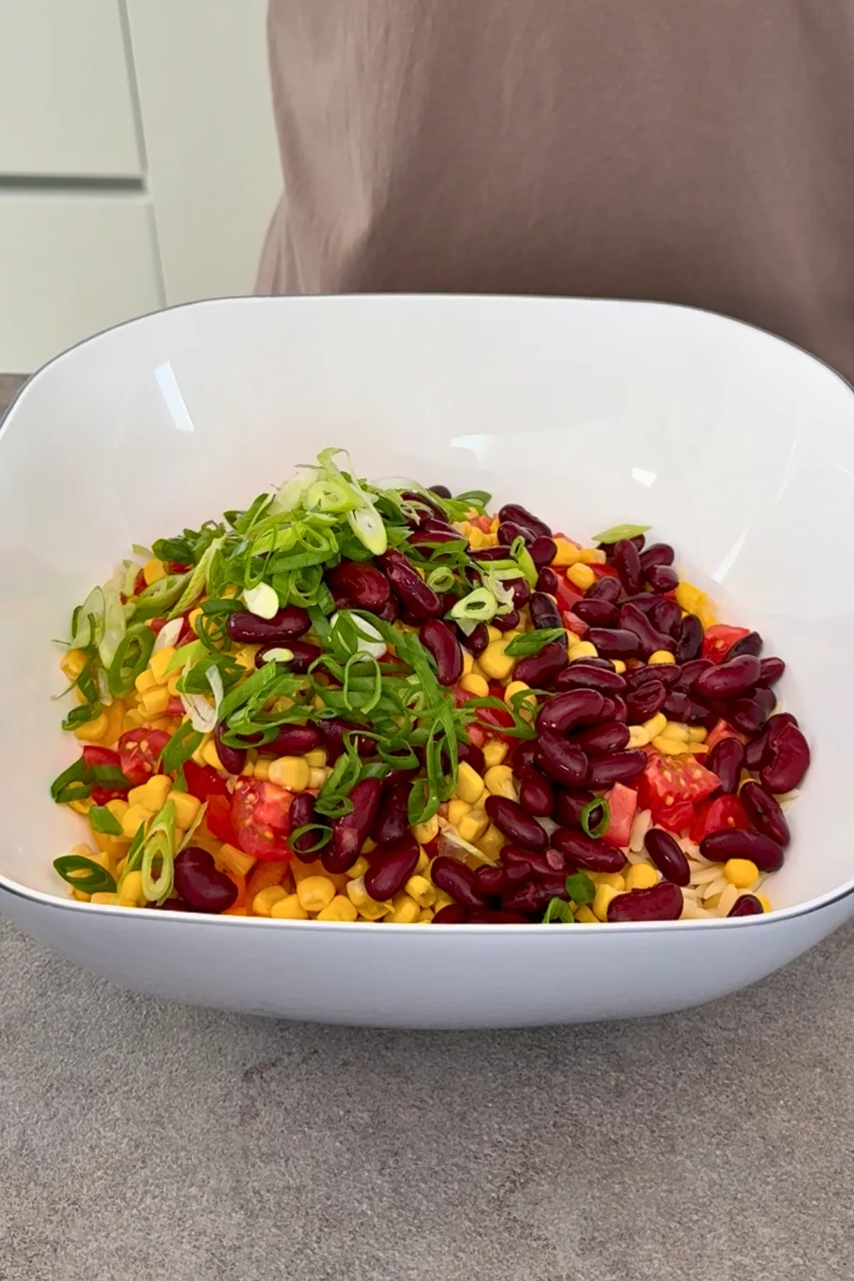 Orzo Nudelsalat Zutaten in großer Schüssel mit Kidneybohnen, Mais, Tomaten und Frühlingszwiebeln