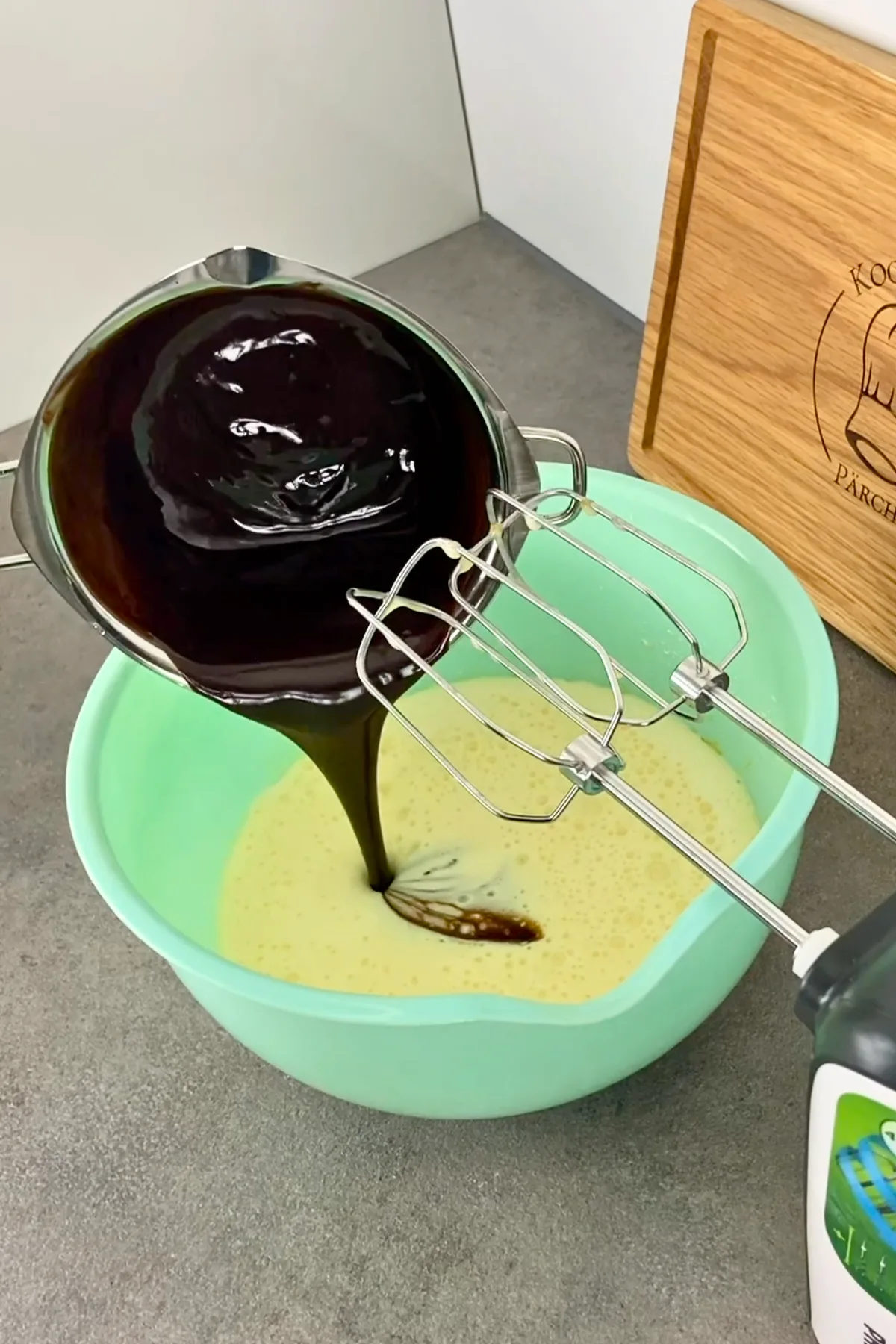 Geschmolzene Schokomasse wird in die Eimasse für Schwarzwälder Kirsch Muffins gegossen