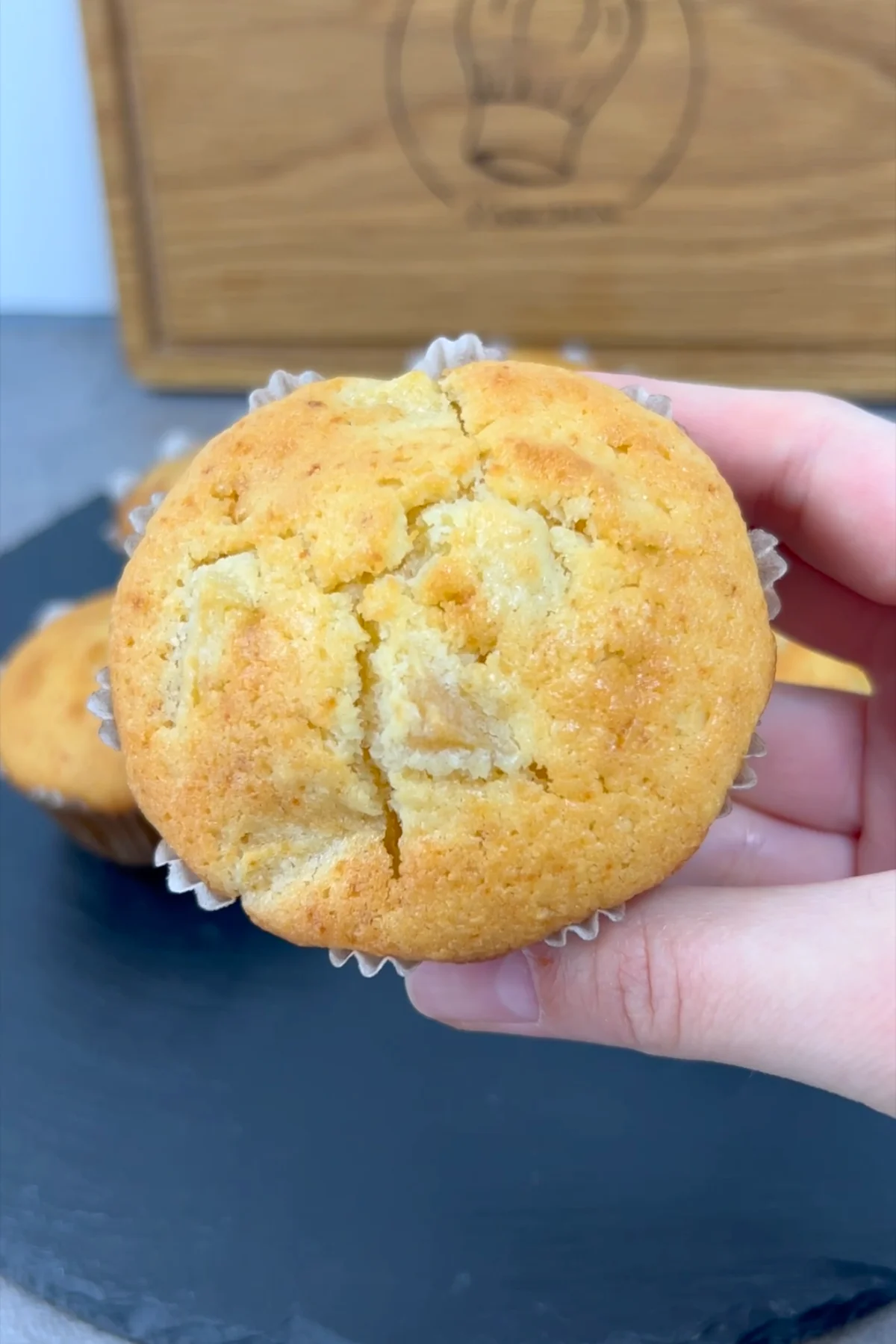 Angebissener Apfelmuffin in der Hand mit sichtbaren Apfelstückchen