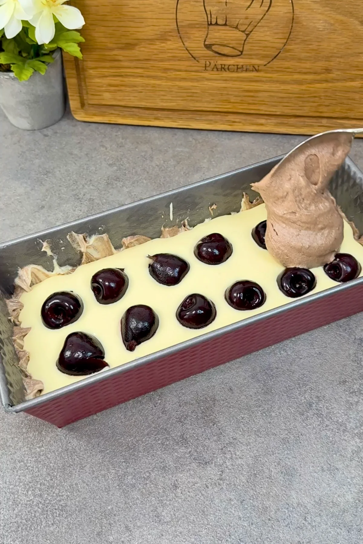 Quarkcreme mit Kirschen in der Kastenform, darauf wird der Schokoteig gesetzt