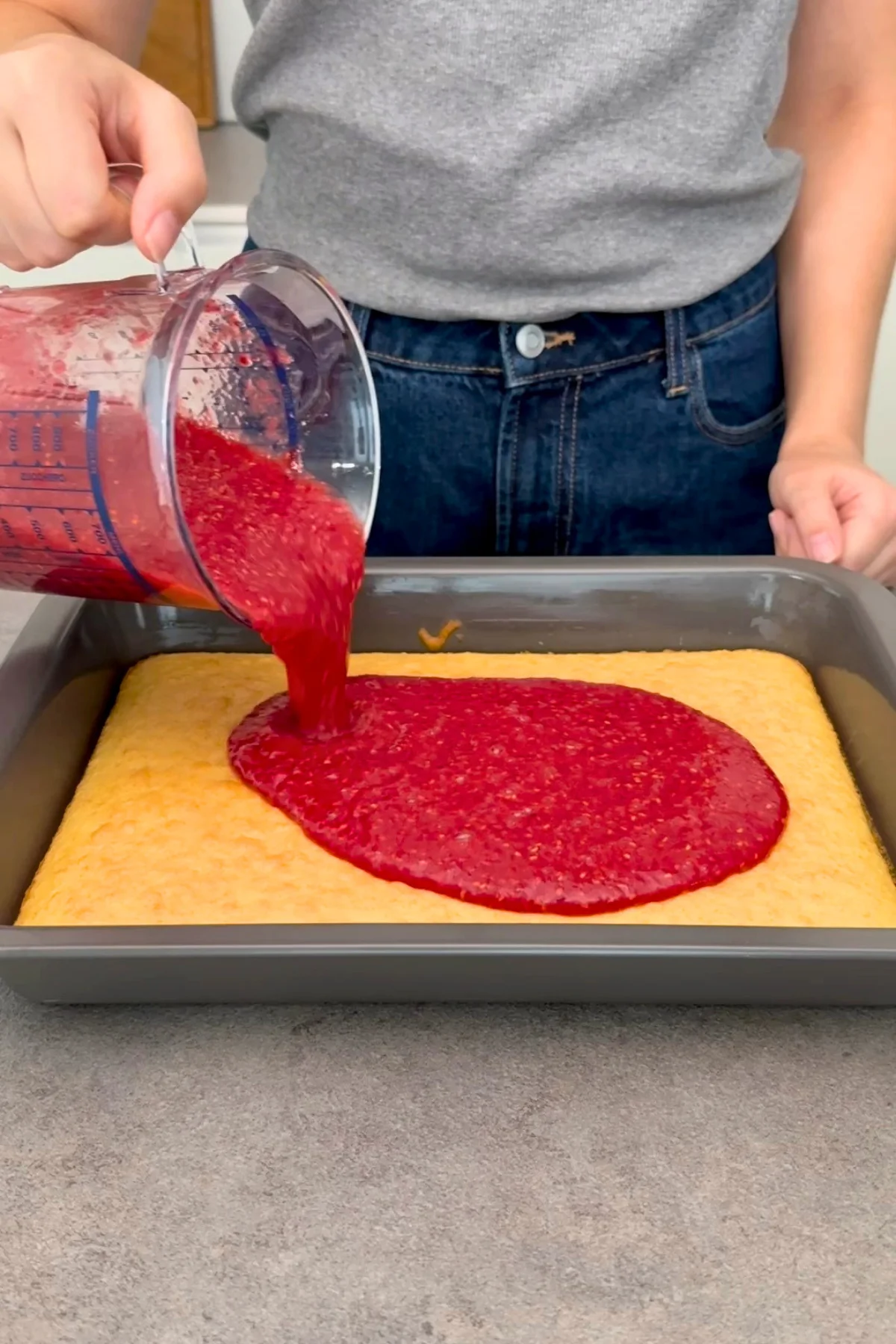 Rote Himbeerfüllung mit Sofort-Gelatine wird auf den fertig gebackenen Biskuitboden gegossen