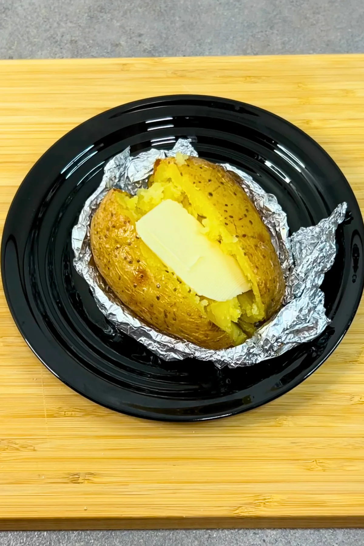 Aufgeschnittene Ofenkartoffel mit einem Stück Butter, das in der heißen Mitte schmilzt