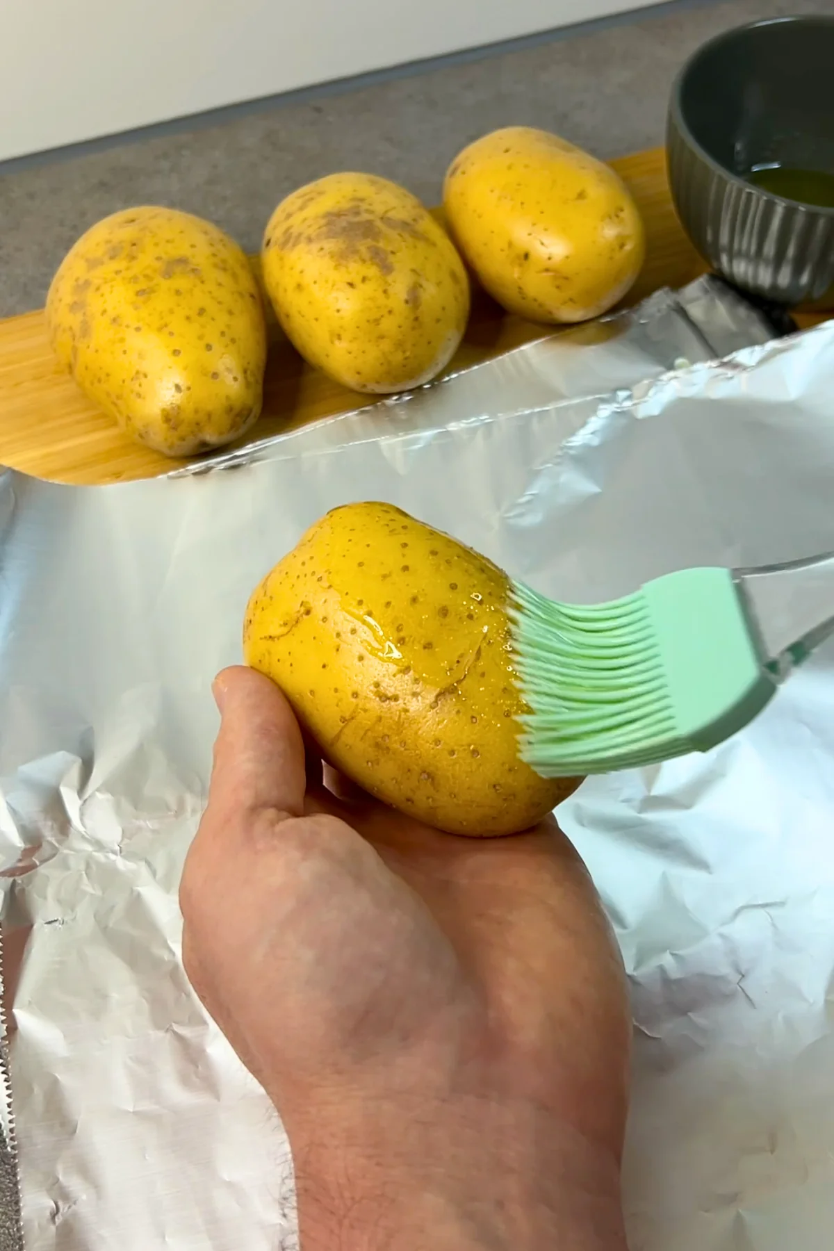 Kartoffel wird mit einem Silikonpinsel rundum mit der Öl-Salz-Marinade bestrichen