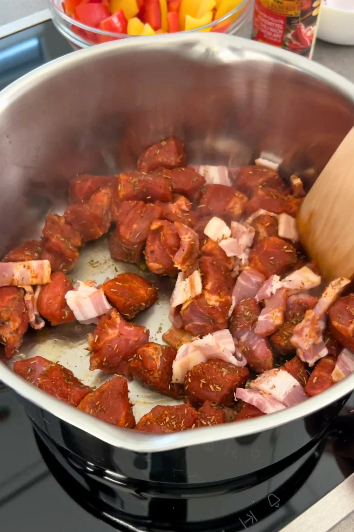 Mariniertes Schweinenackenfleisch mit Speckwürfeln im Topf vor dem Anbraten