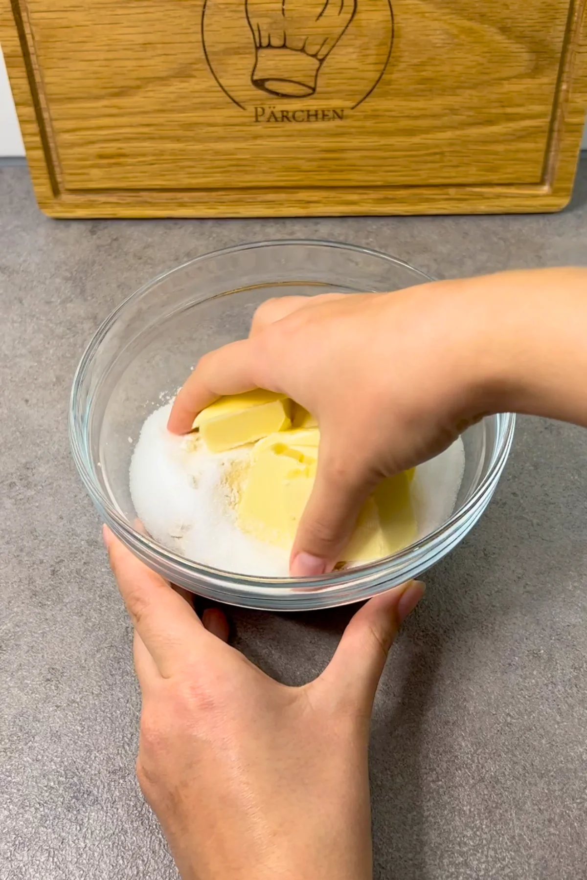 Mehl, Zucker und kalte Butterstücke werden in der Glasschüssel mit den Händen zu Streuseln verknetet