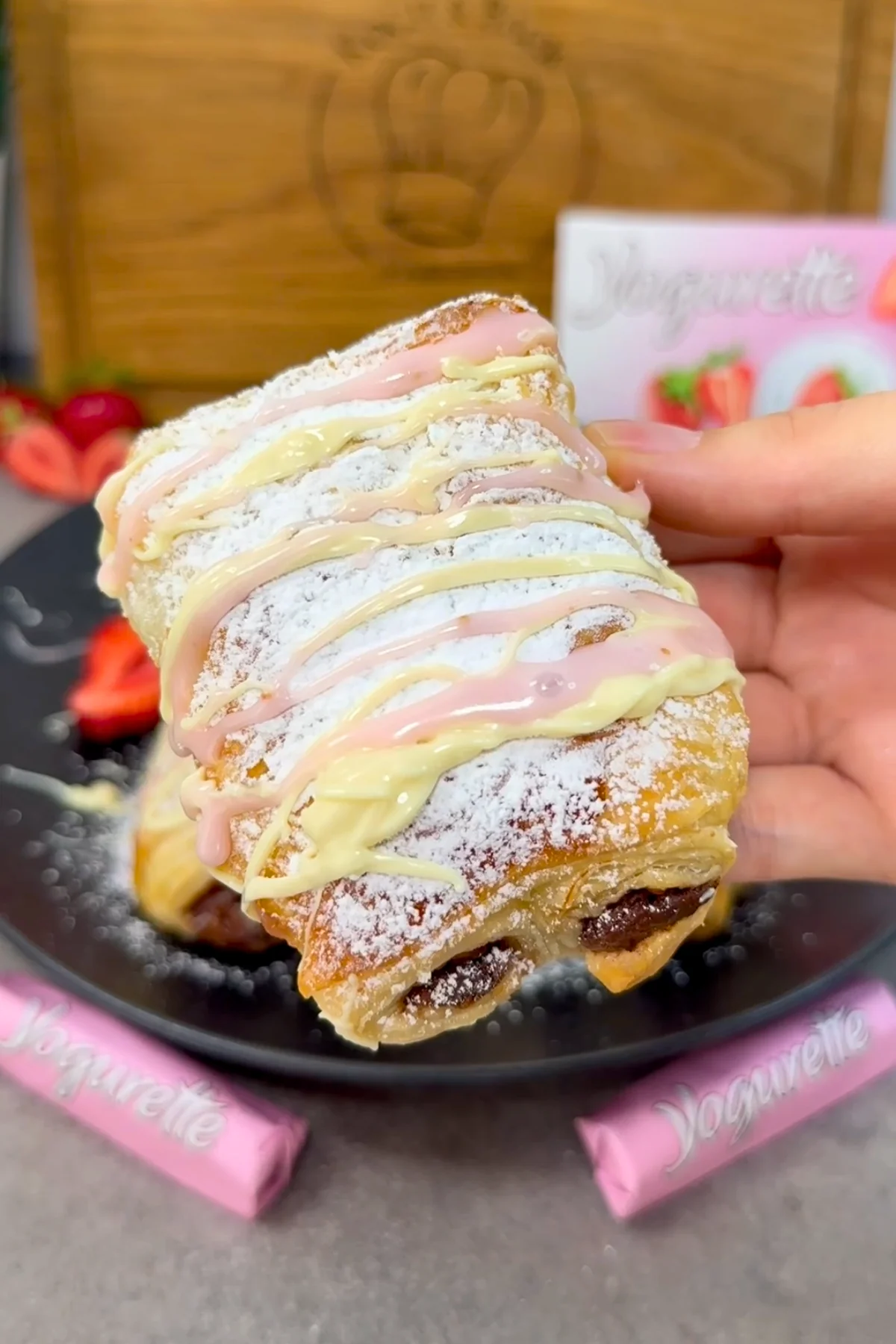 Yogurette Croissant von oben in der Hand gehalten, mit weißer und rosa Schokolade verziert