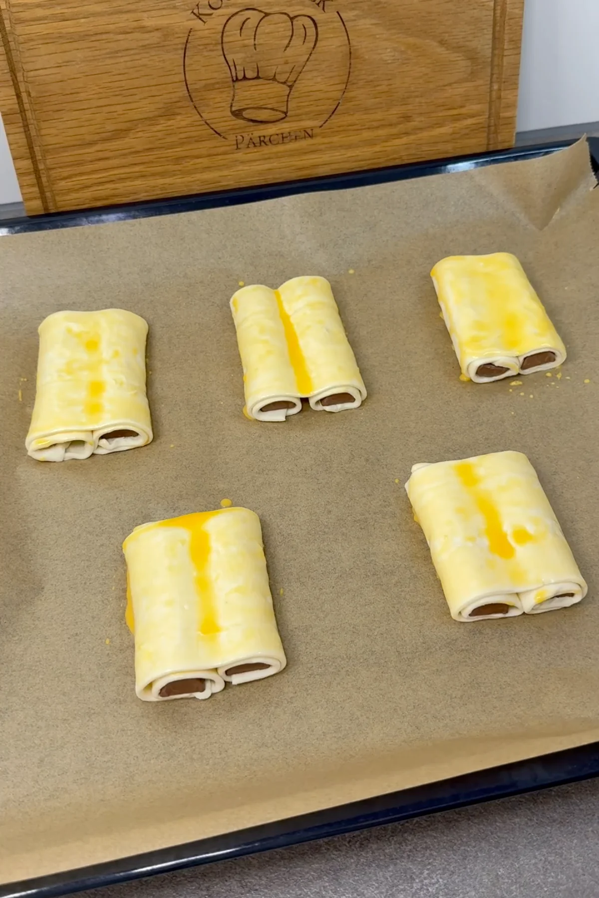 Fünf ungebackene Yogurette Croissants auf dem Backblech, mit Eigelb bestrichen