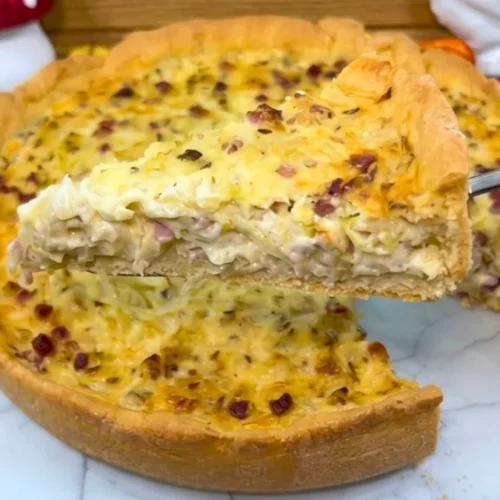 Angeschnittener schwäbischer Krautkuchen auf weißem Teller, ein Stück wird mit dem Heber herausgehoben