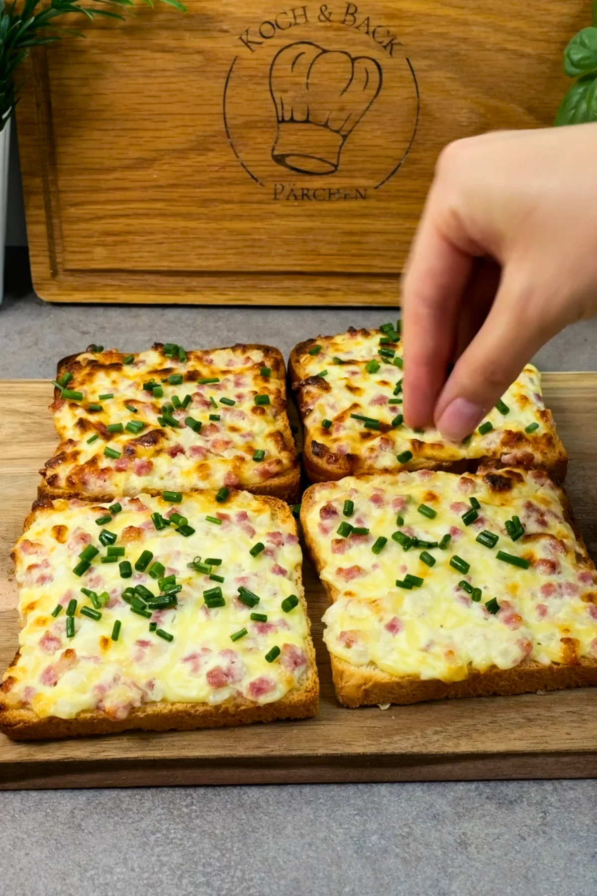 Frisch geschnittener Schnittlauch wird von Hand über die gebackenen Flammkuchentoasts gestreut