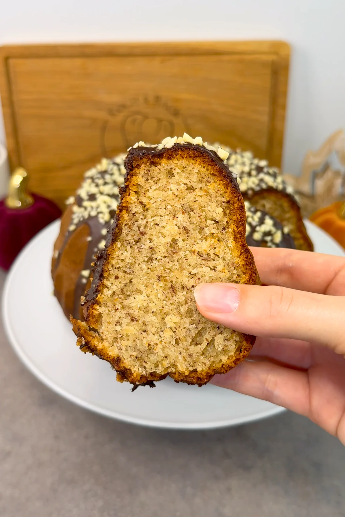Ein Stück Nusskuchen wird in der Hand gehalten, die feinen Nussstückchen sind in der saftigen Krume gut zu erkennen