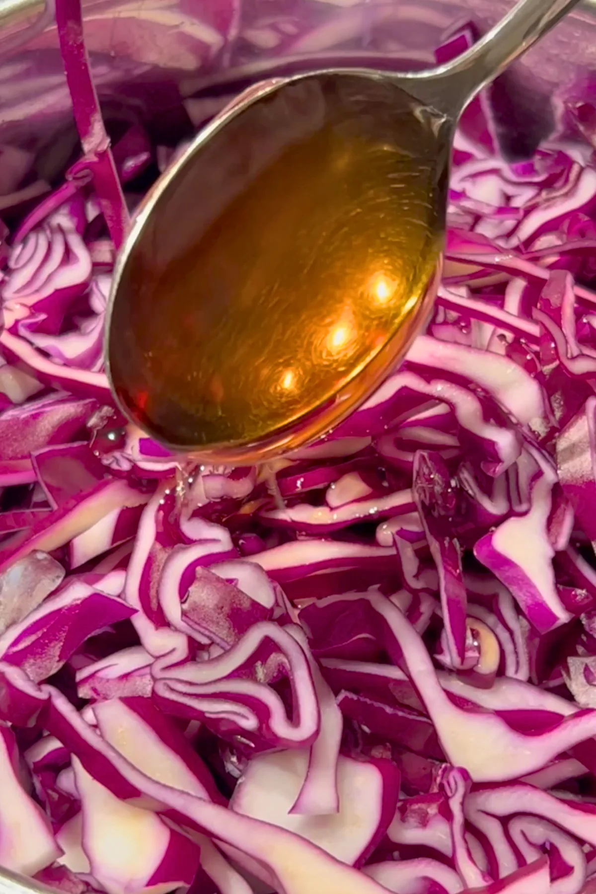 Ein Löffel Agavendicksaft wird über den rohen, in Streifen geschnittenen Rotkohl gegeben
