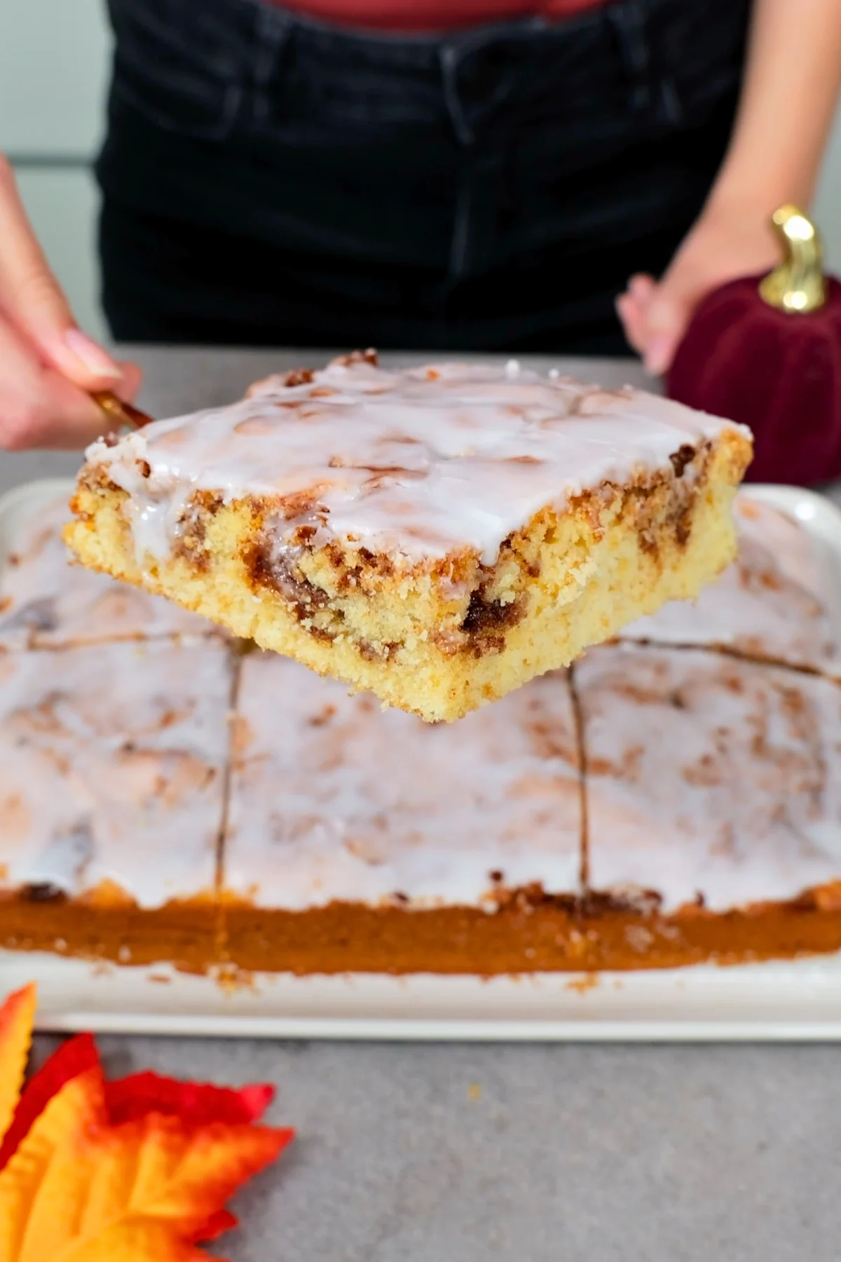 Nahaufnahme eines Kuchenstücks mit deutlich sichtbaren Zimtadern im fluffigen Teig und dickem Zuckerguss obenauf